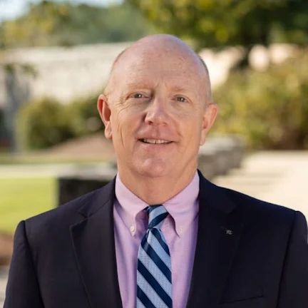 Headshot of Billy Curtis. Billy is wearing a suit and is standing outside.