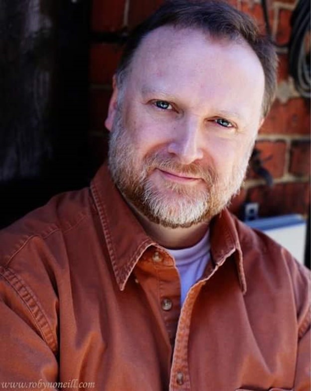 Headshot of Dave Fuller. Dave is wearing a corduroy button-up shirt and is smiling at the camera.