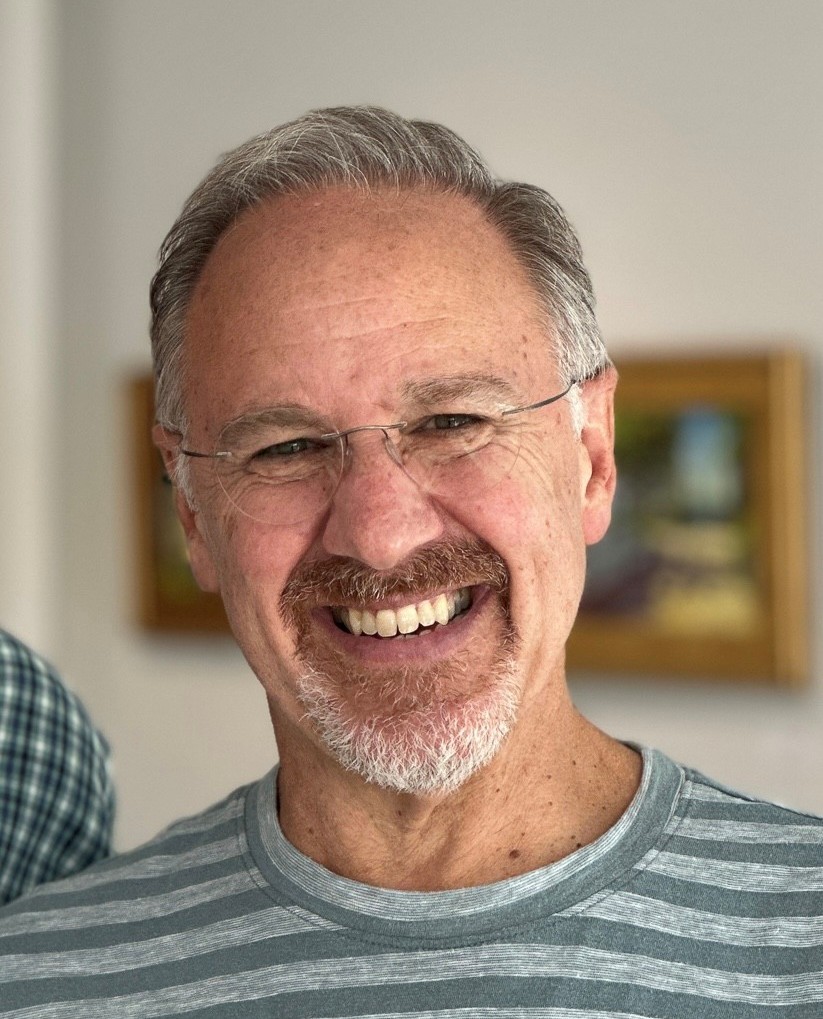 Headshot of Paul. Paul is a white man wearing a striped shirt.