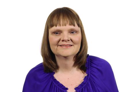 Headshot of Ricky Enger. She has short brown hair and is wearing a purple blouse.