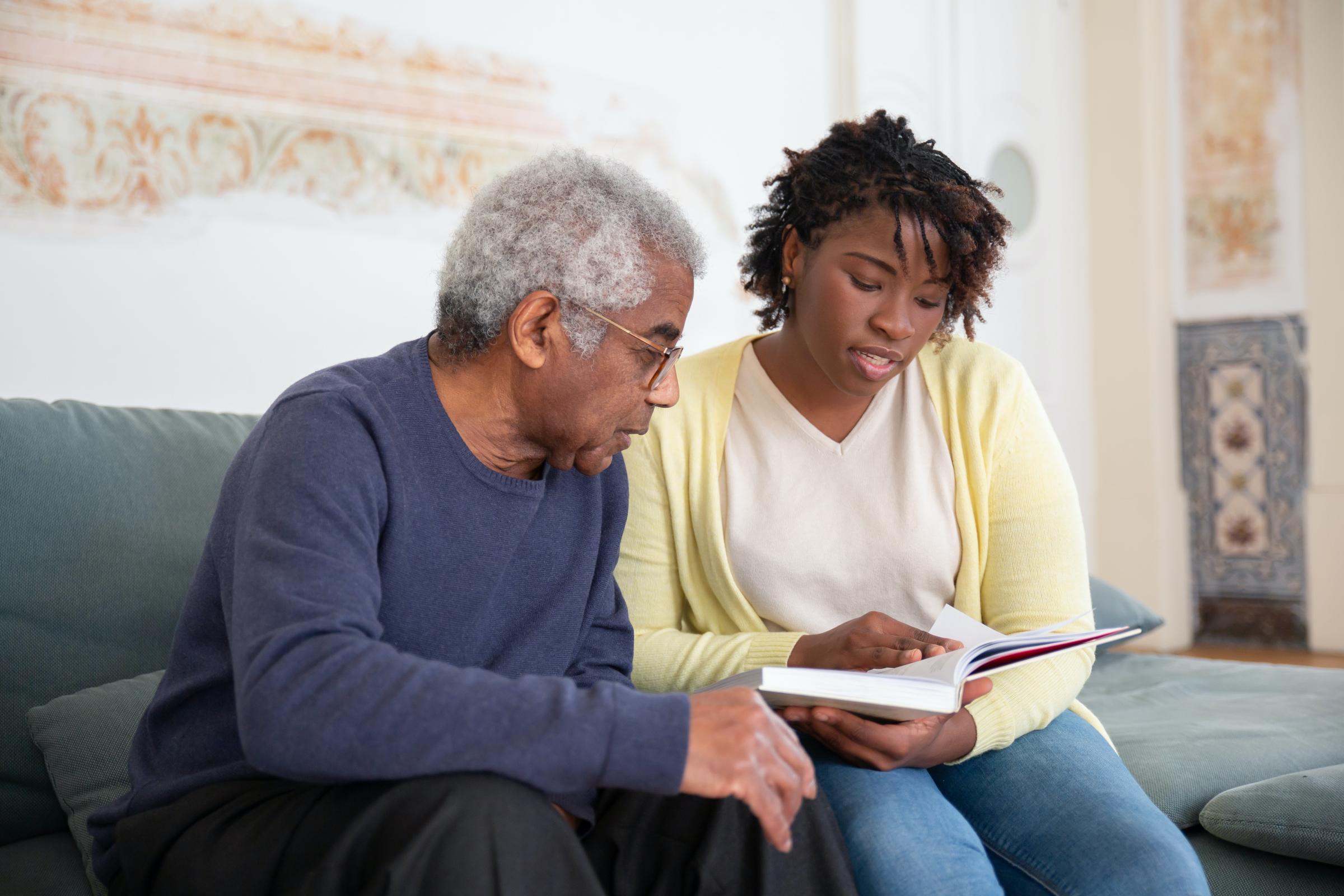 Young women reading to an older gentlemen 