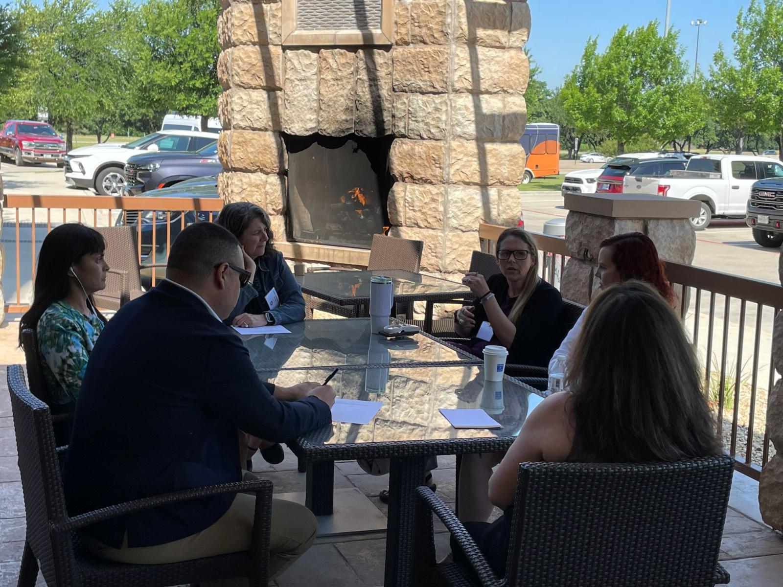 Attendees sitting at a glass table outside of the hotel.