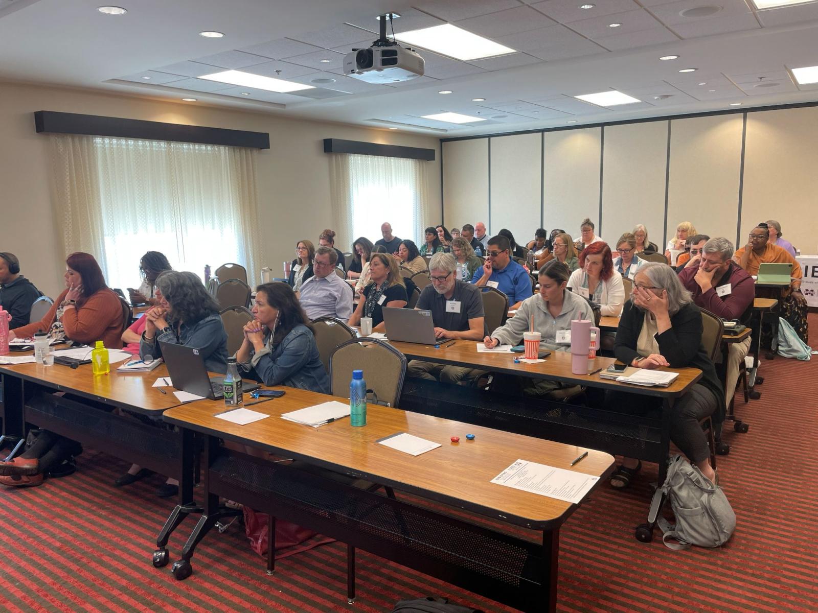 All attendees sitting in a conference room engaged in a presentation.
