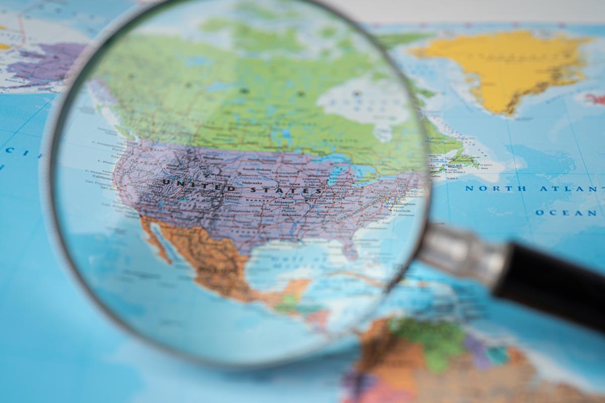A magnifying glass close up to a colorful world map with North America shown through the glass.