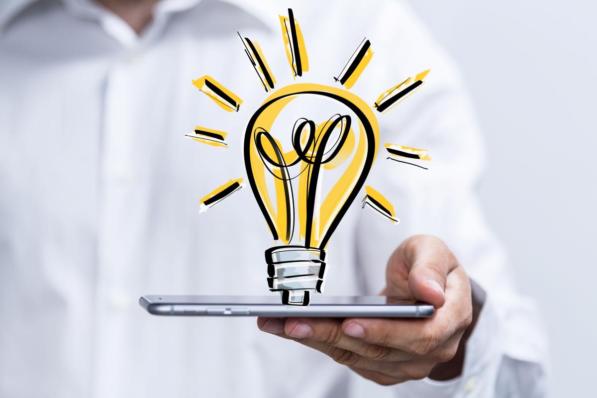 Hand holding a tablet with a drawing of a lightbulb above.